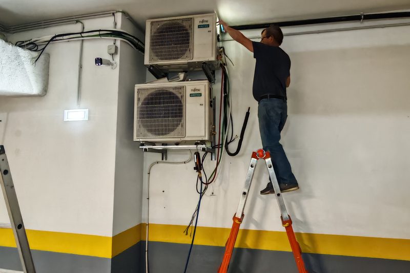 Técnico em escada a instalar duas unidades exteriores Fujitsu Airstage numa garagem