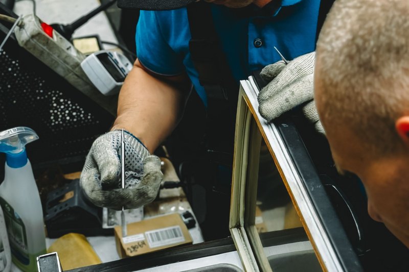 Técnicos a reparar a vedação da porta de uma arca frigorífica comercial