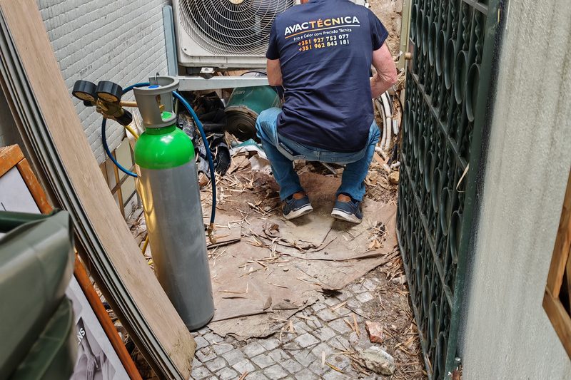 Técnico a intervencionar uma unidade exterior, com garrafa de gás